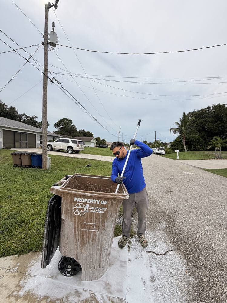 Crew member scrubbing the inside of a foamed trash bin