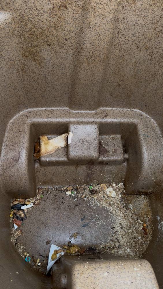 Inside of trash bin before cleaning, with trash and grime